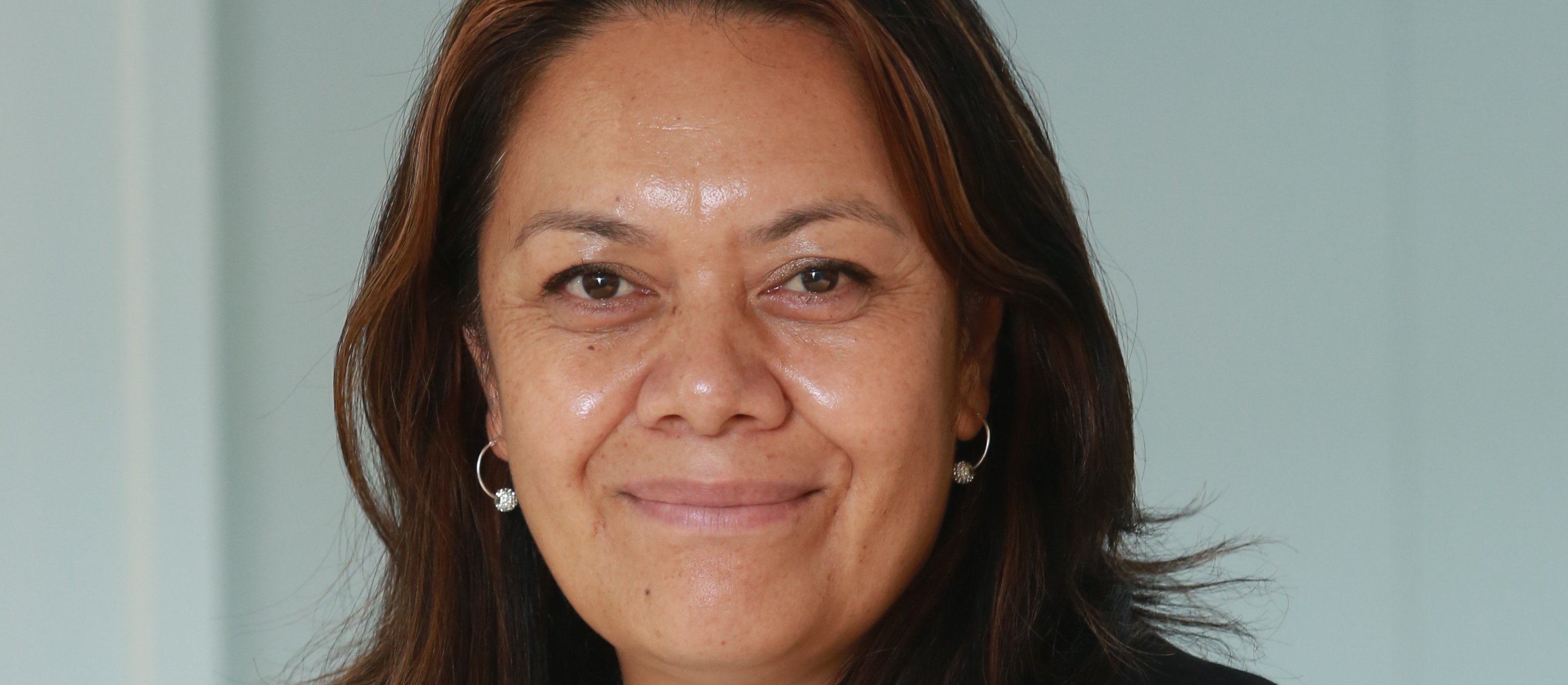 Margie Apa, wearing a white top with a flower and black blazer, smiling at camera