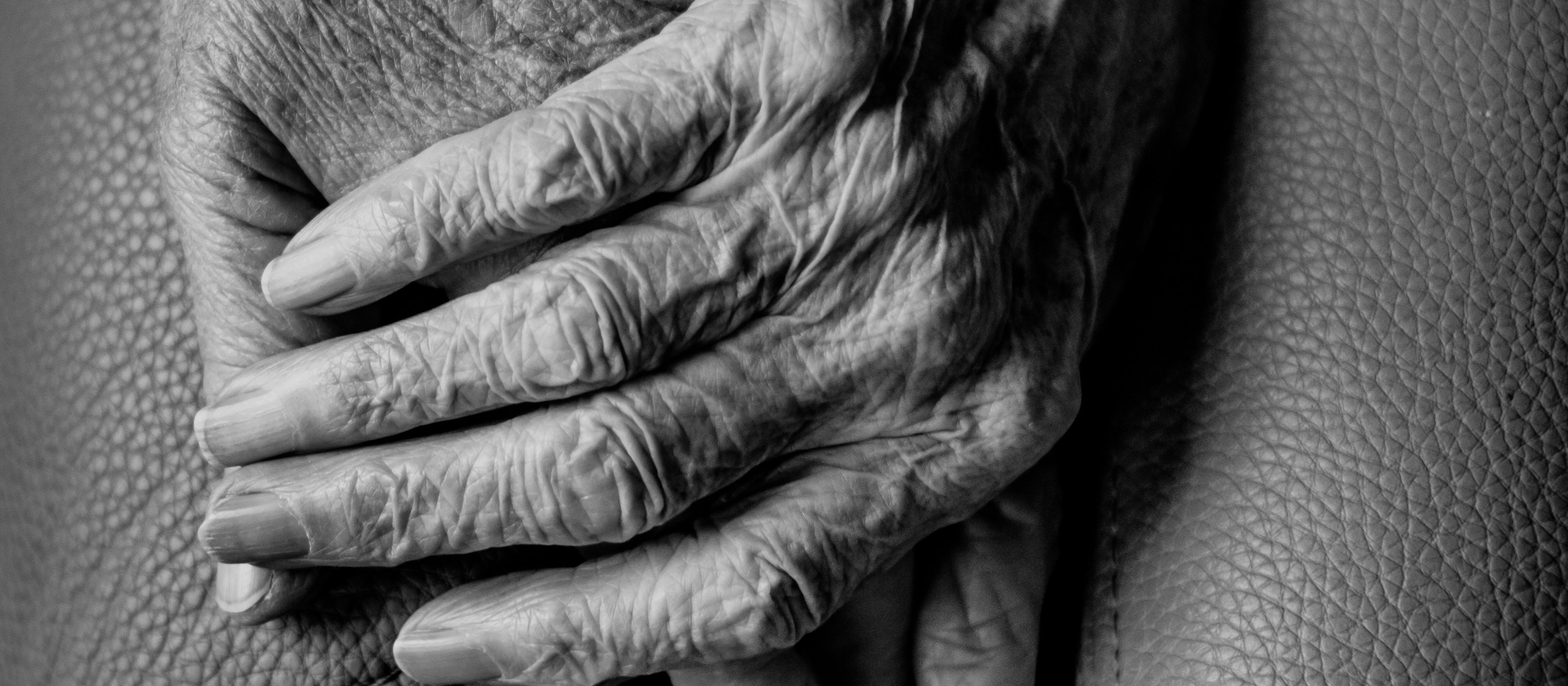 black and white image, close-up of hands of two old people holding hands