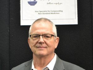 Man with glasses looking at camera, sign above head reads Compound Labs