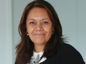 Margie Apa, wearing a white top with a flower and black blazer, smiling at camera