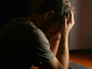 Man at desk, head in hands CR LARAM on Unsplash